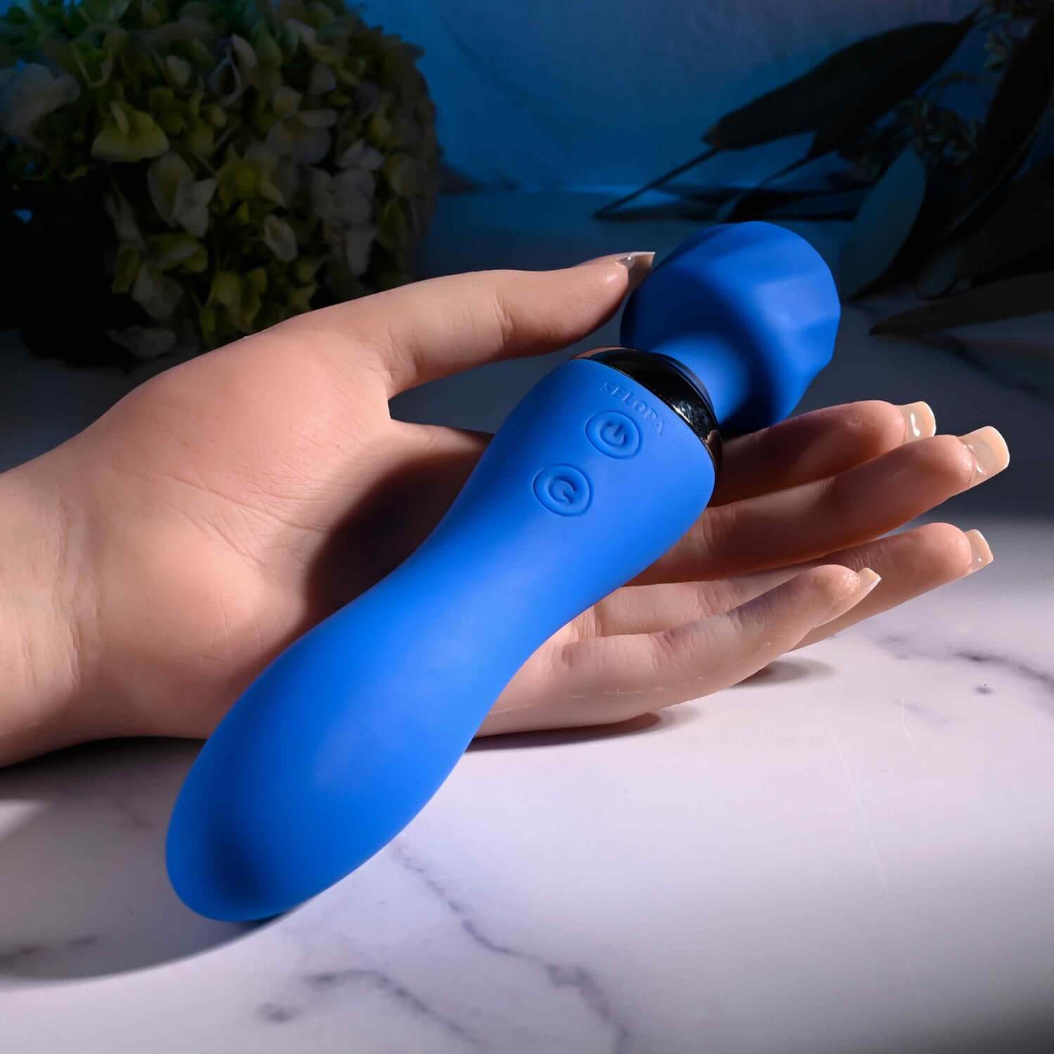 Hand holding a blue wand massager with textured head and controls, showcasing its stylish design and ergonomic shape.