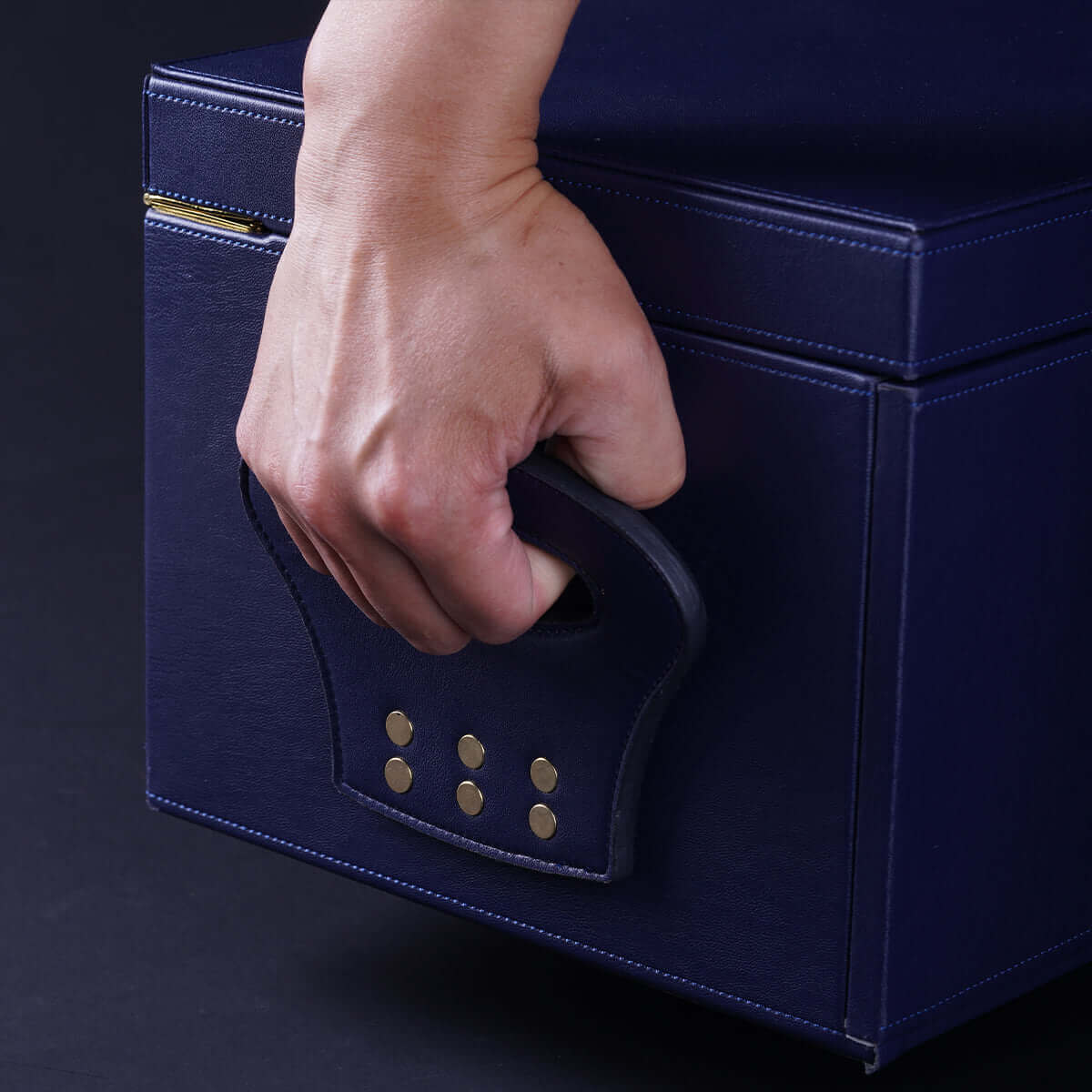 Hand gripping the handle of the UPKO Black Label Deluxe Kit, showcasing its luxurious faux leather design.