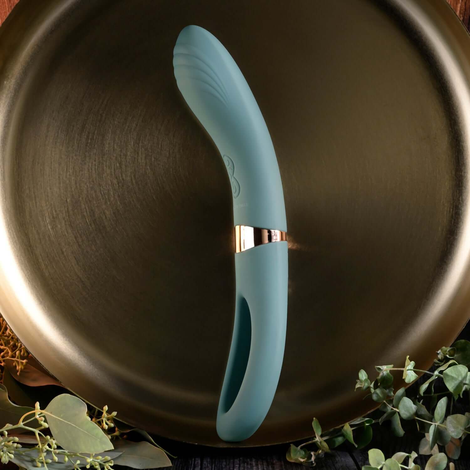 Chick Flick Tongue Mint Vibrator on a decorative plate, showcasing its sleek design and curved ribbed shaft.