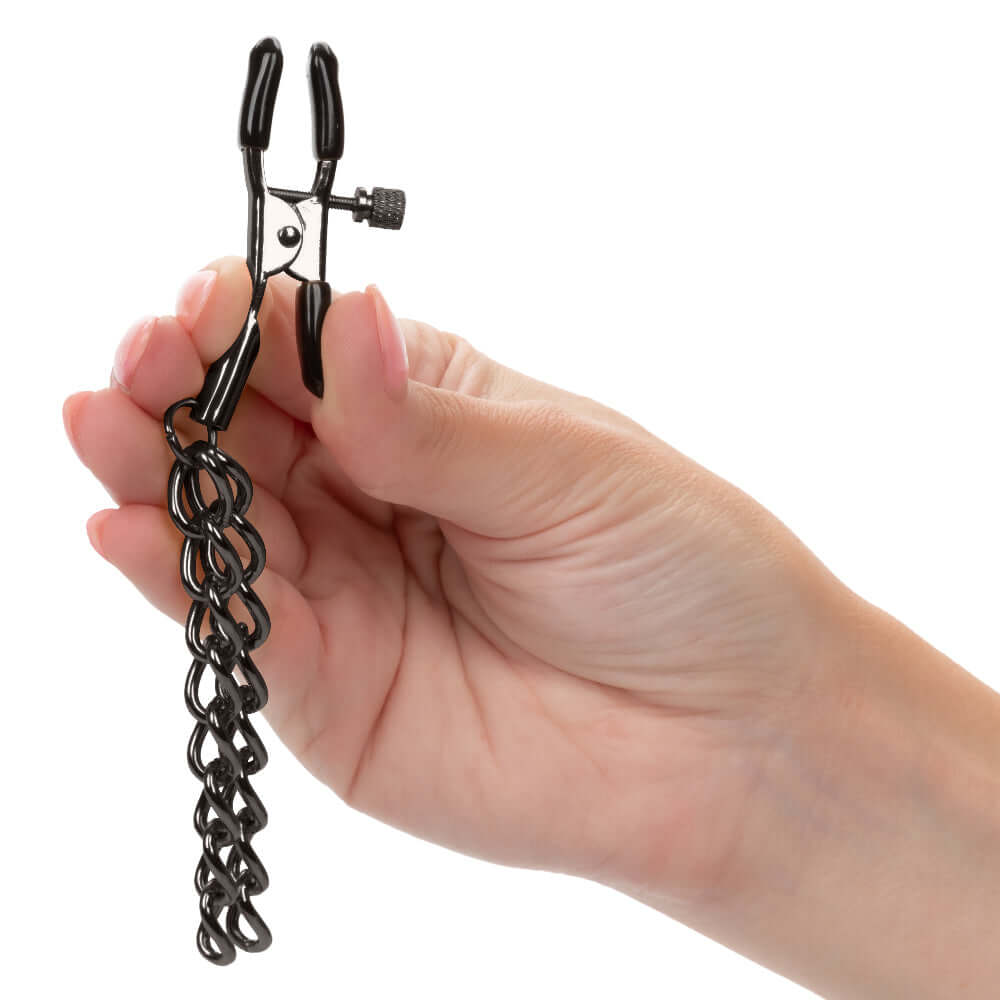 Hand holding Euphoria Collection Chain Nipple Clamps in black with adjustable design and soft pads for sensory pleasure.