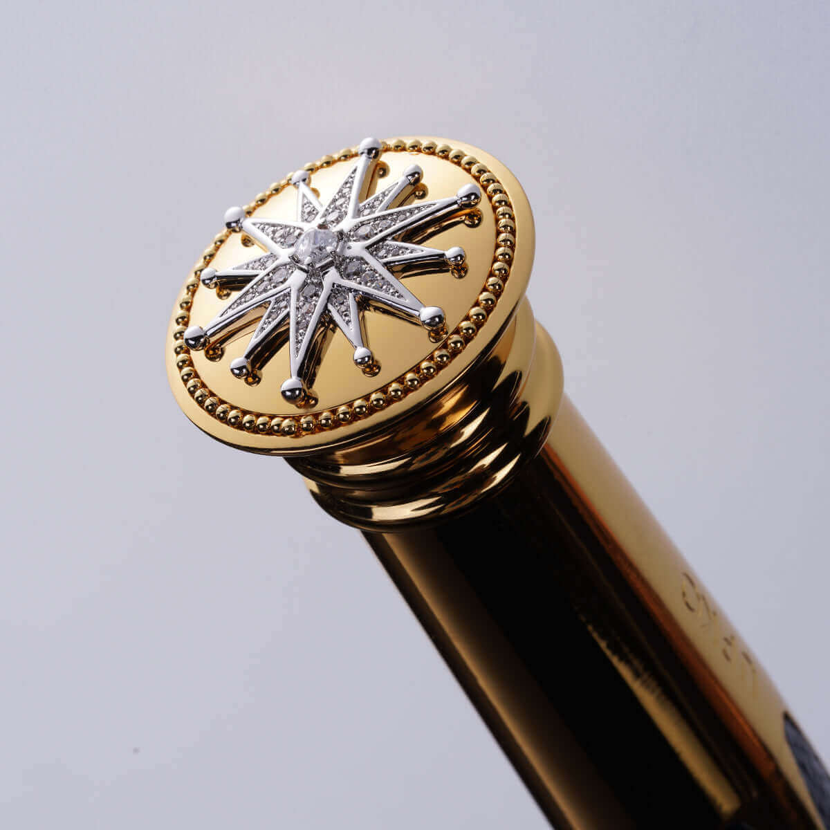 Close-up of a luxurious golden bottle cap featuring a starburst design with sparkling accents.