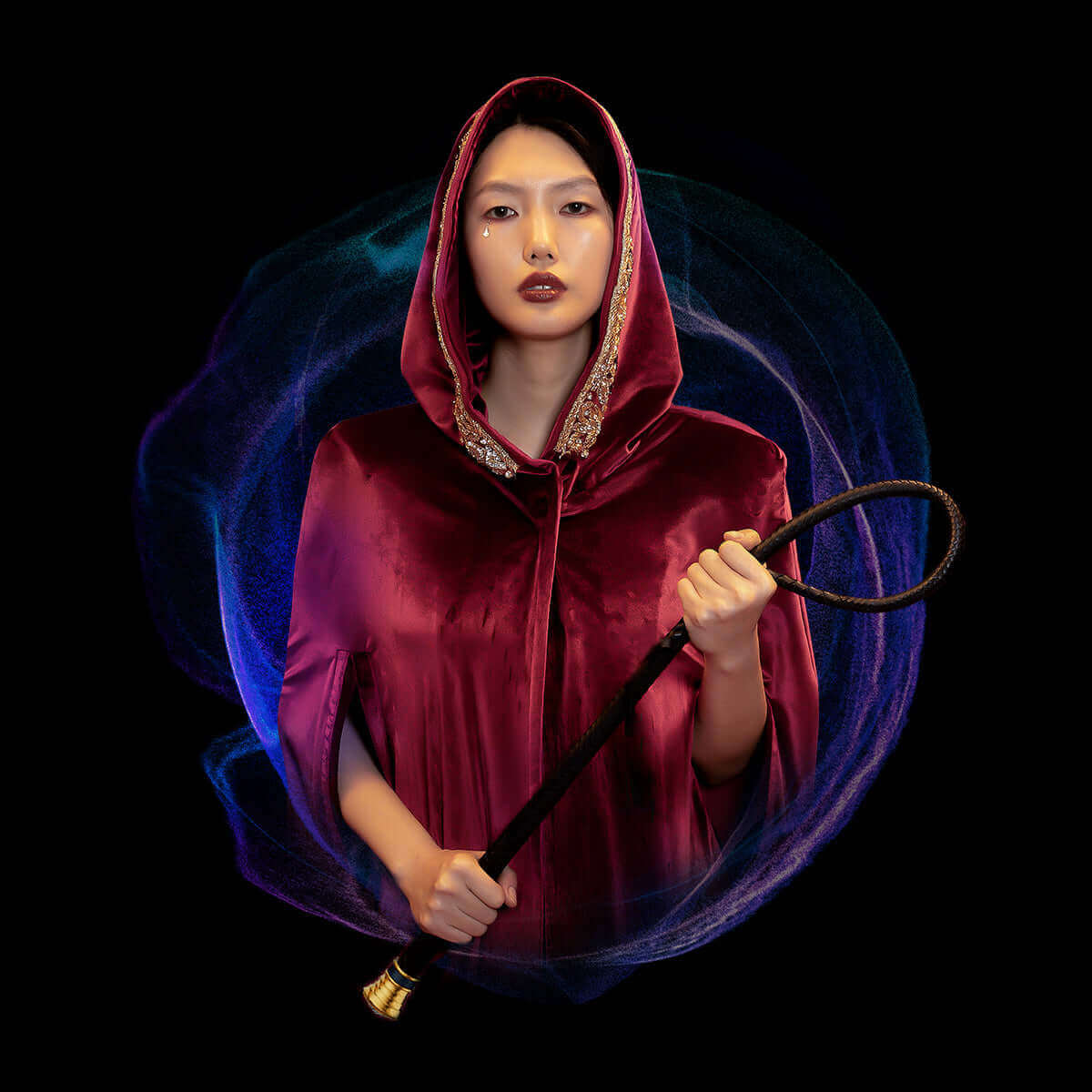 Elegant woman in a velvet hooded cloak holding a whip, set against a cosmic background.