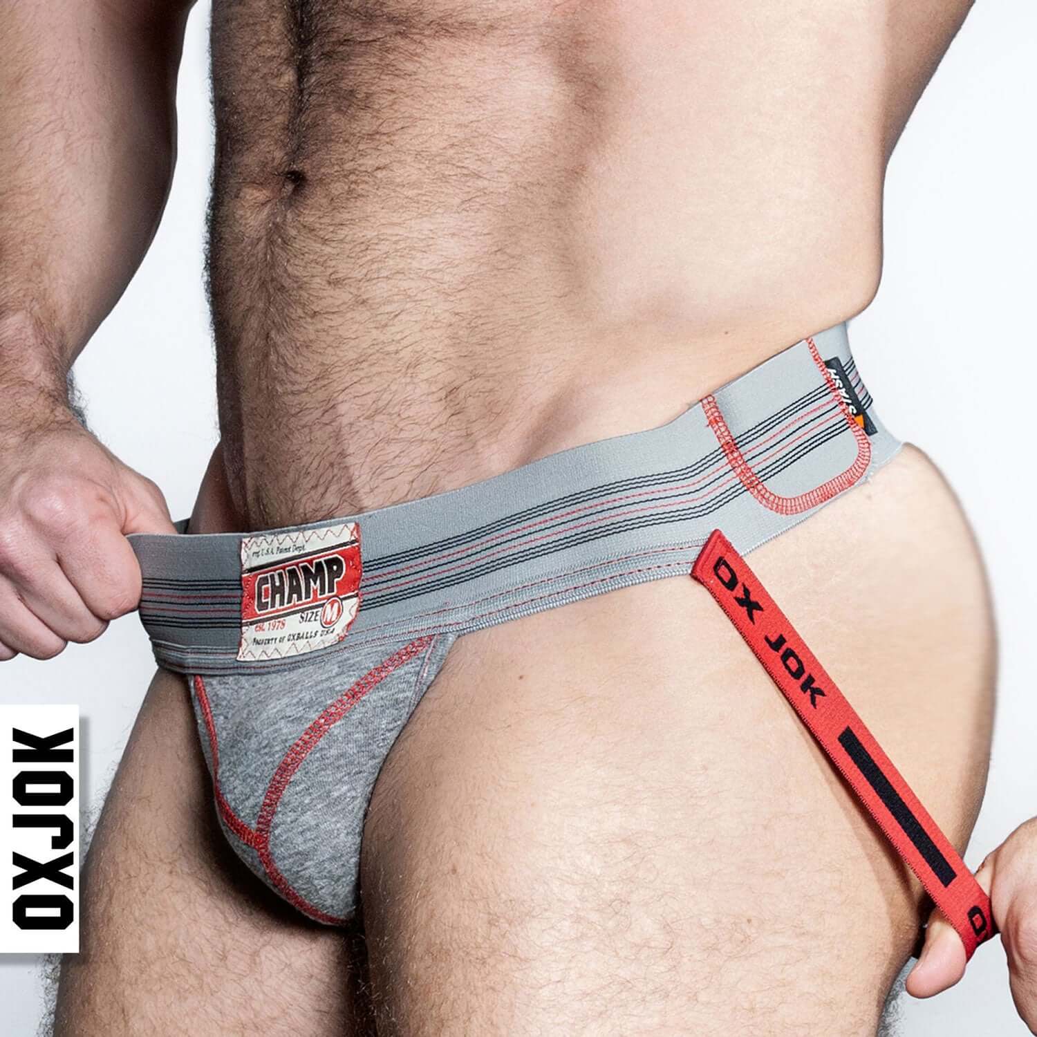 Man wearing Champ Vintage Sweatshirt Jockstrap in Gray Heather with plush pouch, vintage woven waistband label, and red accents.