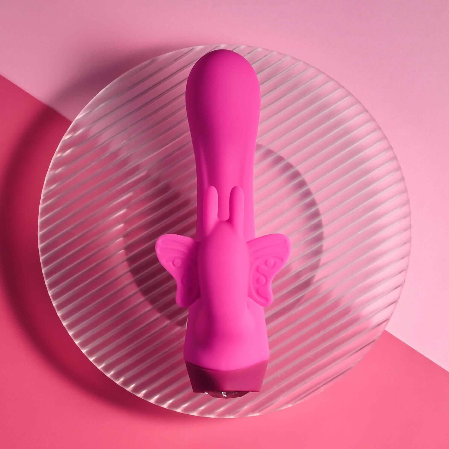 Pink Butterfly Love Rabbit Vibrator on a circular glass plate, showcasing its sleek design and butterfly stimulator.