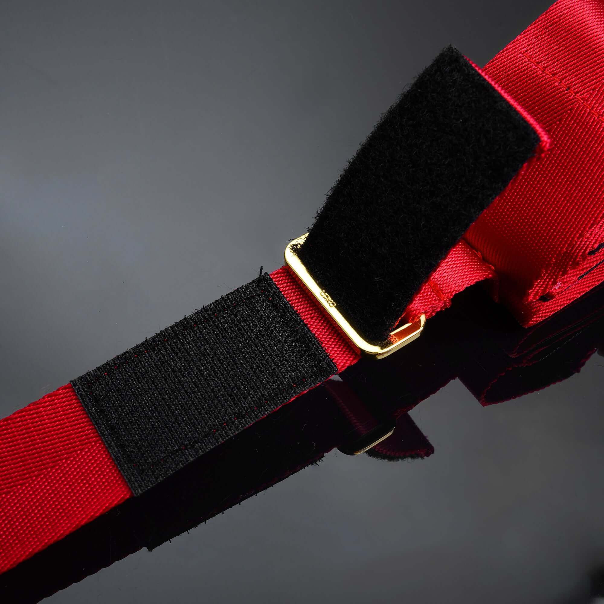 Close-up of Bowknot Hogtie Portable Bondage Gear red strap with black velcro and gold buckle detail.