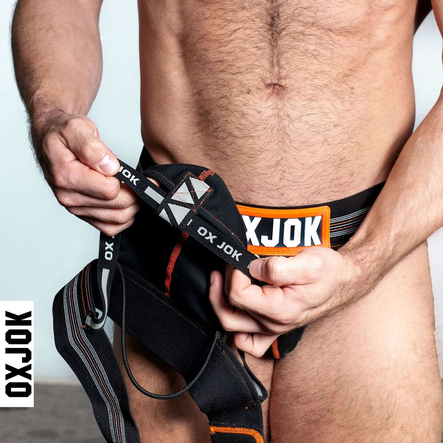 Model wearing Oxjok Slingjock Upthrust Slider-Strap Jock, adjusting the slider-strap for comfort and support.