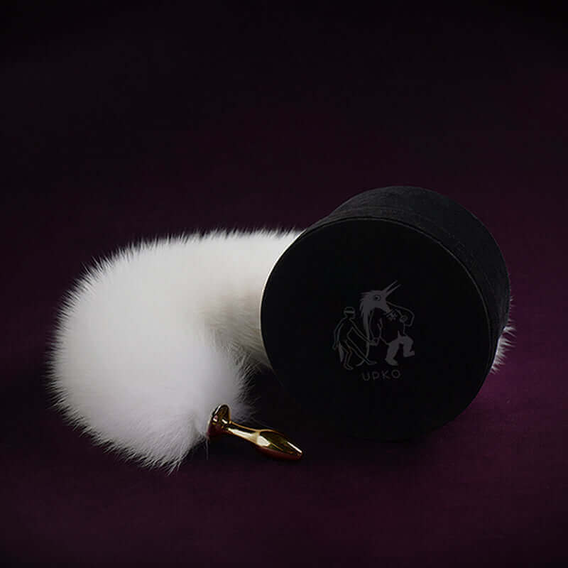 White fox fur tail small butt plug with 24K gold-plated metal tip by UPKO, elegantly packaged on a dark background.