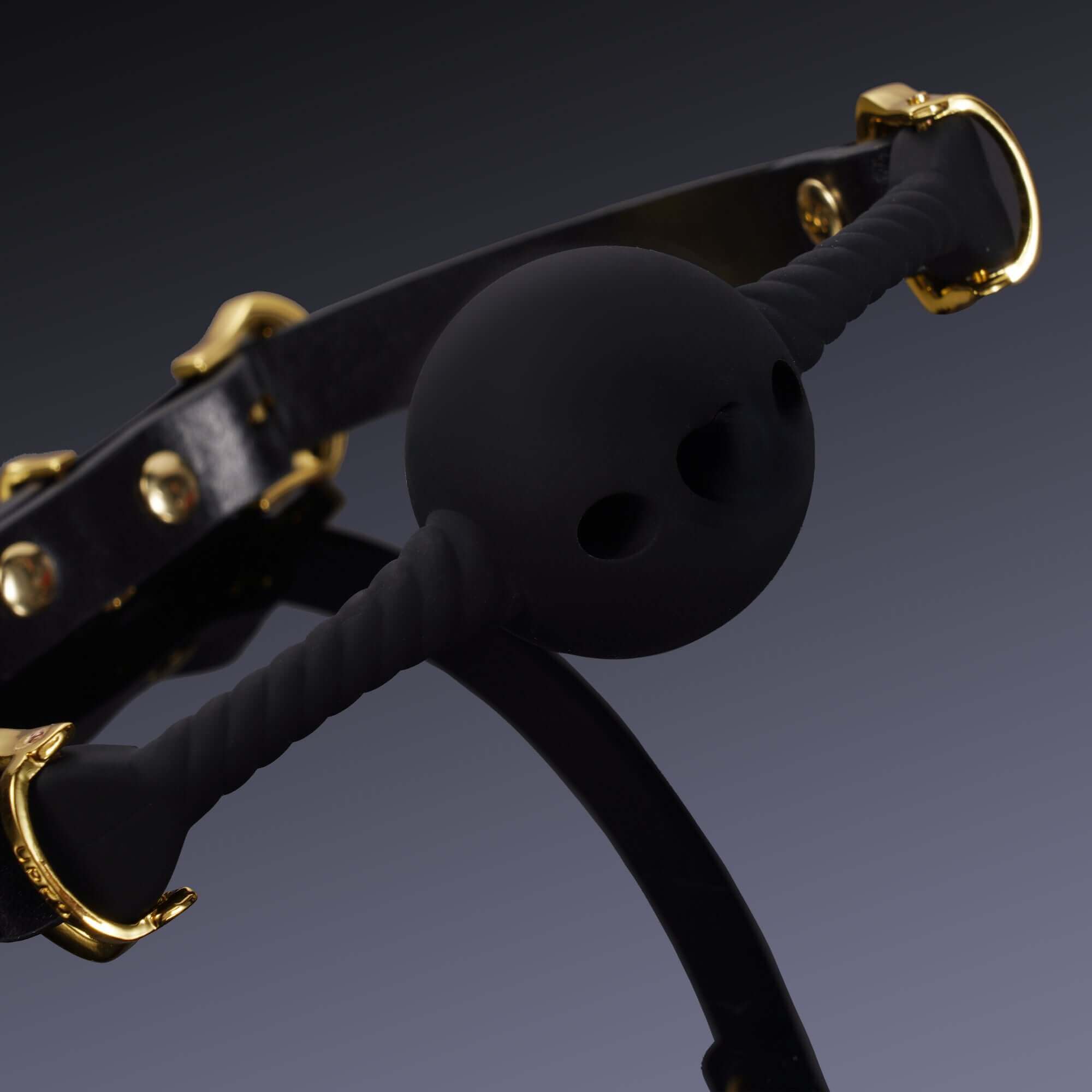 Black heart-shaped silicone mouth gag with gold hardware and Italian leather strap, emphasizing submission and comfort.