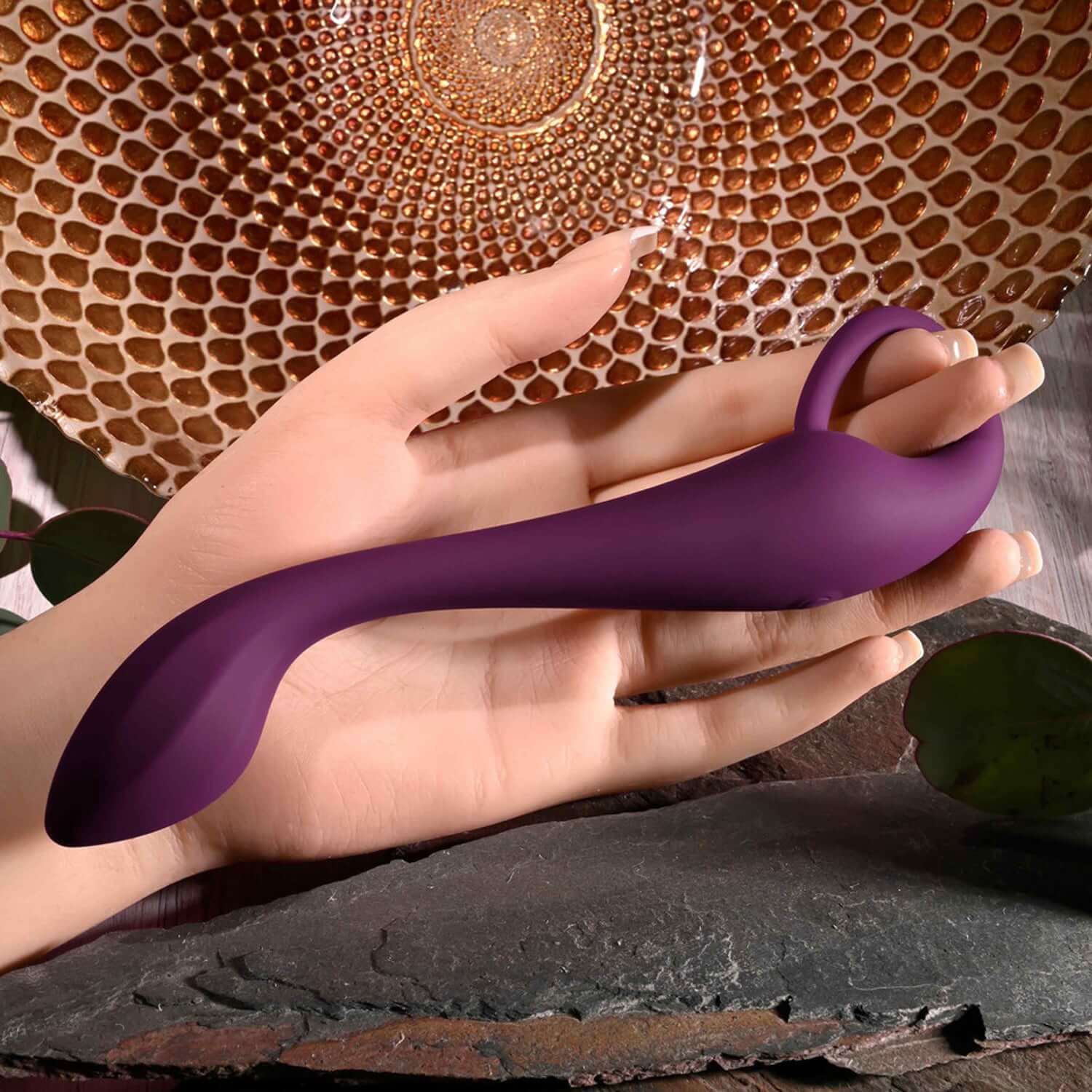 Burgundy Lochness G-spot vibrator held in hand, showcasing its gentle curve and ergonomic design for pleasurable use.