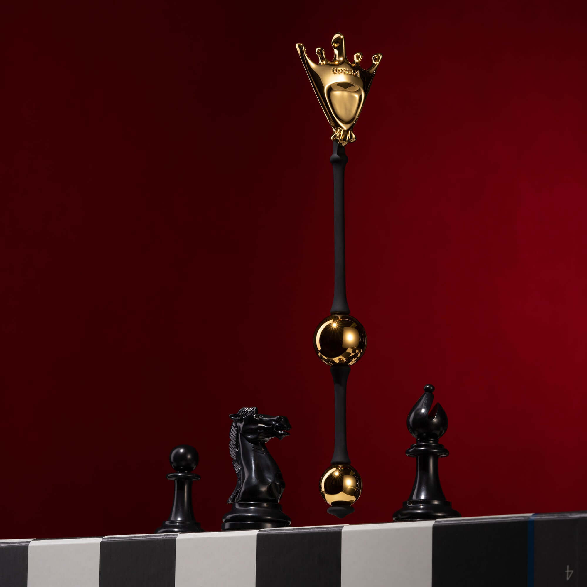 "The Chess Collection - Queen Premium Metal Pleasure Balls with black and gold chess pieces on a striped surface."