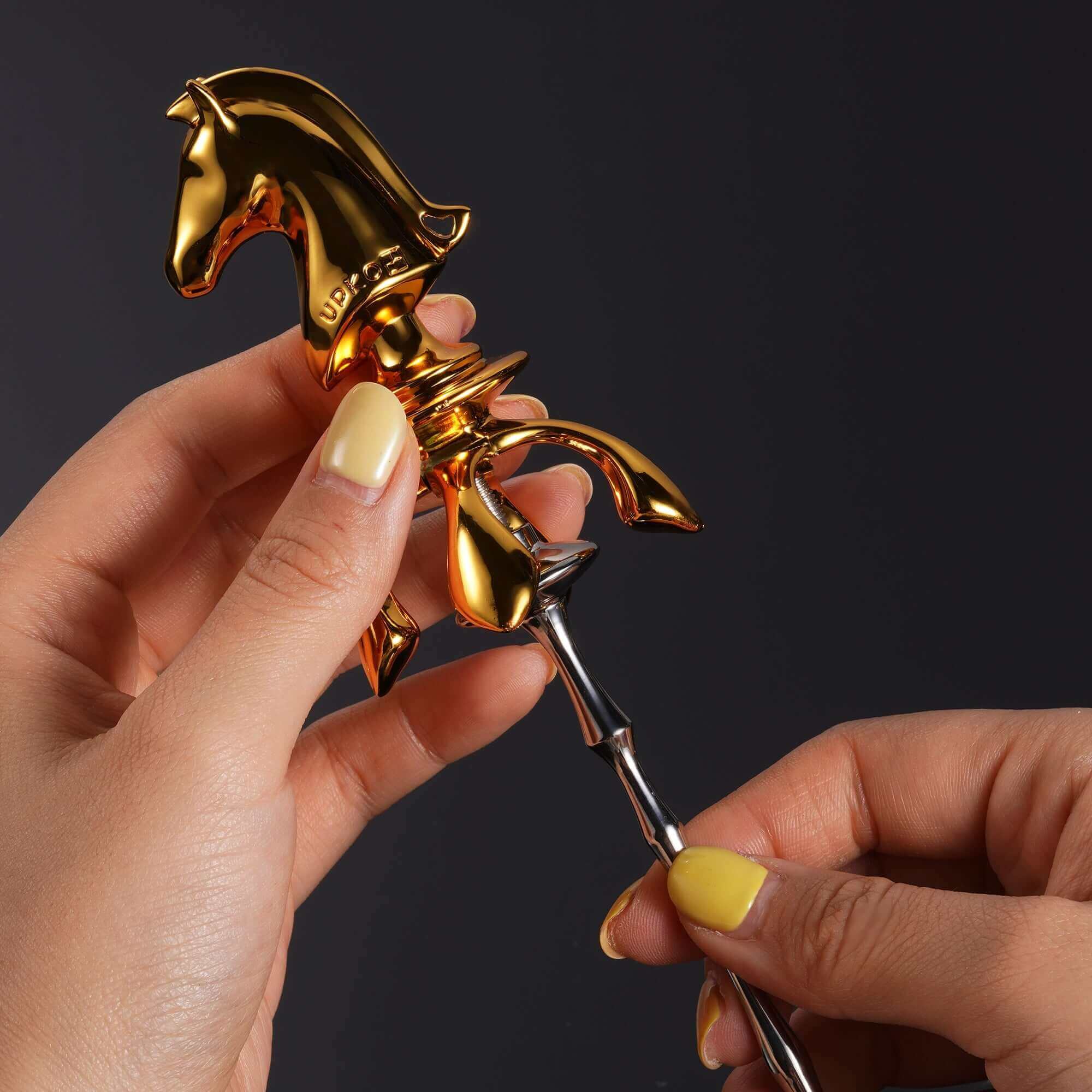 Close-up of hands holding gold Knight urethral sound plug from The Chess Collection, showcasing its unique design.