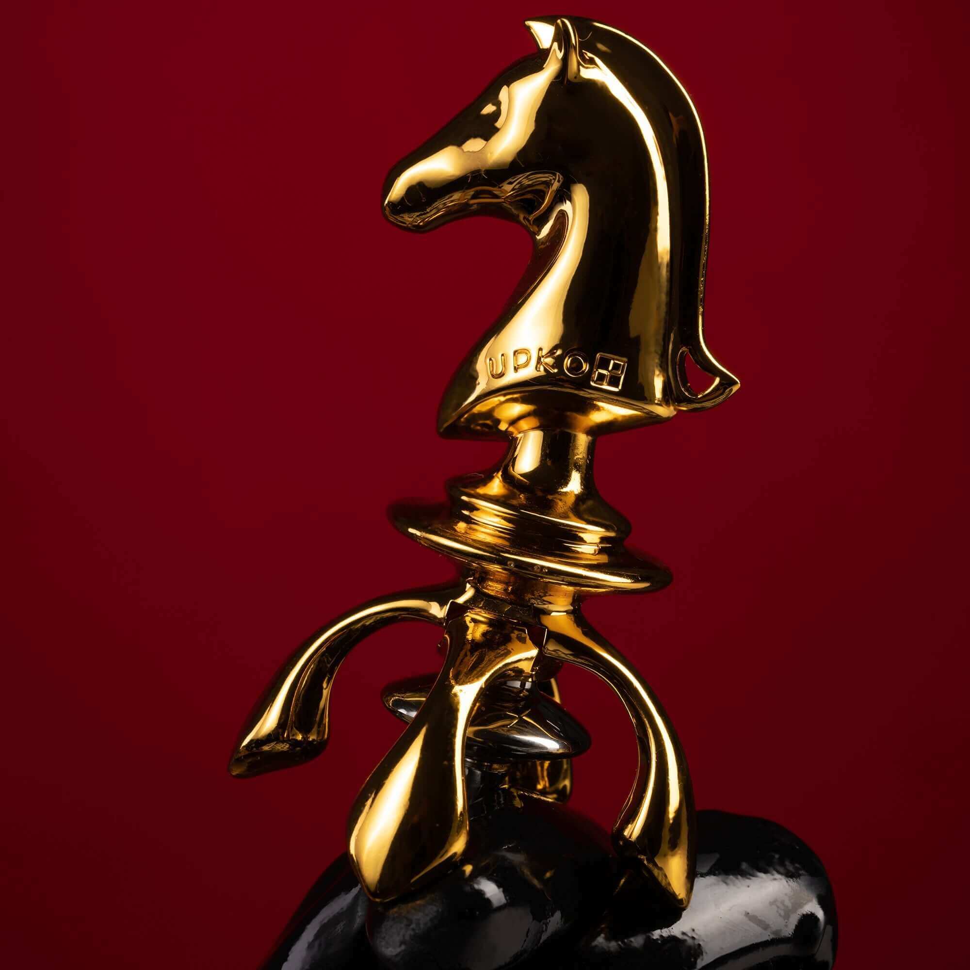 Gold knight-shaped urethral sound plug on a black base against a red background, from "The Chess" collection.