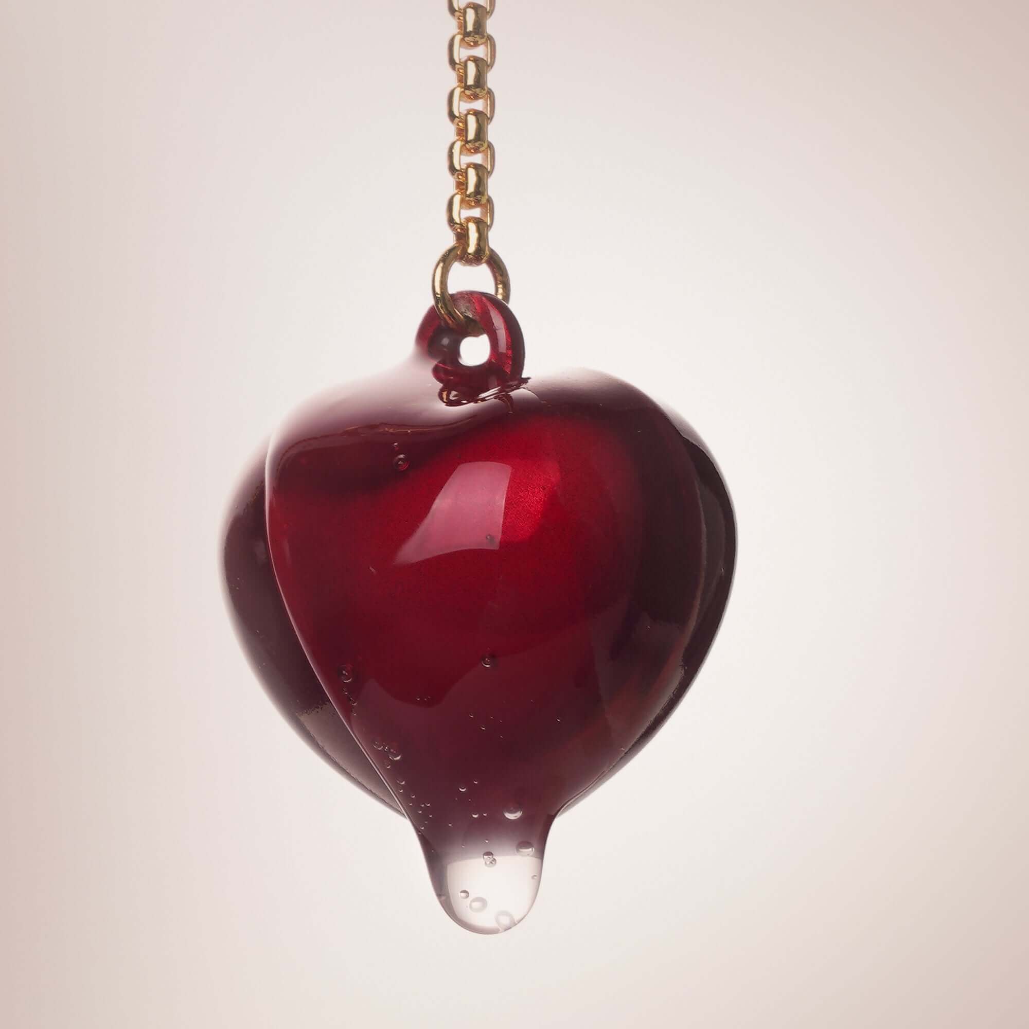 Red heart-shaped decorative pendant with a chain, elegantly designed with a glossy finish.