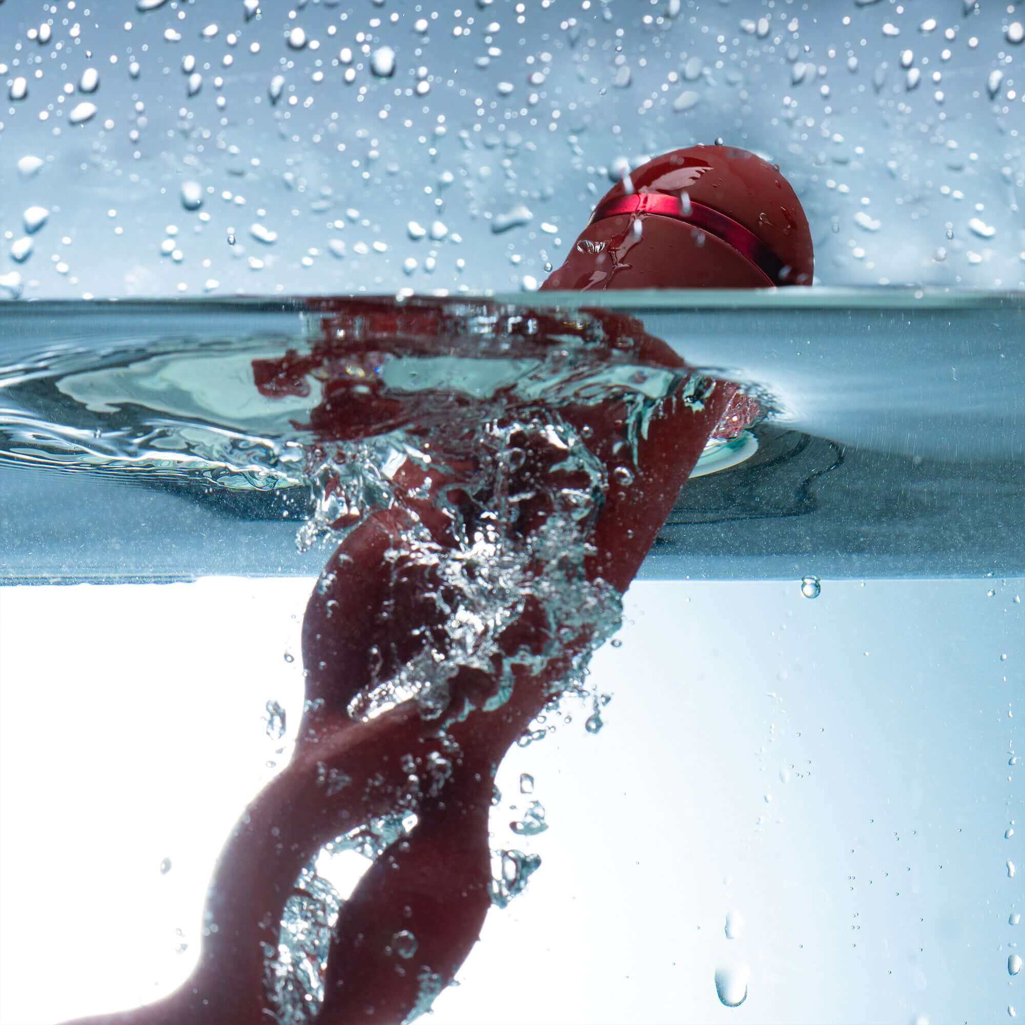 UEROS Multi-motor Pulse Vibrator Red submerged in water, showcasing its unique design and waterproof feature.