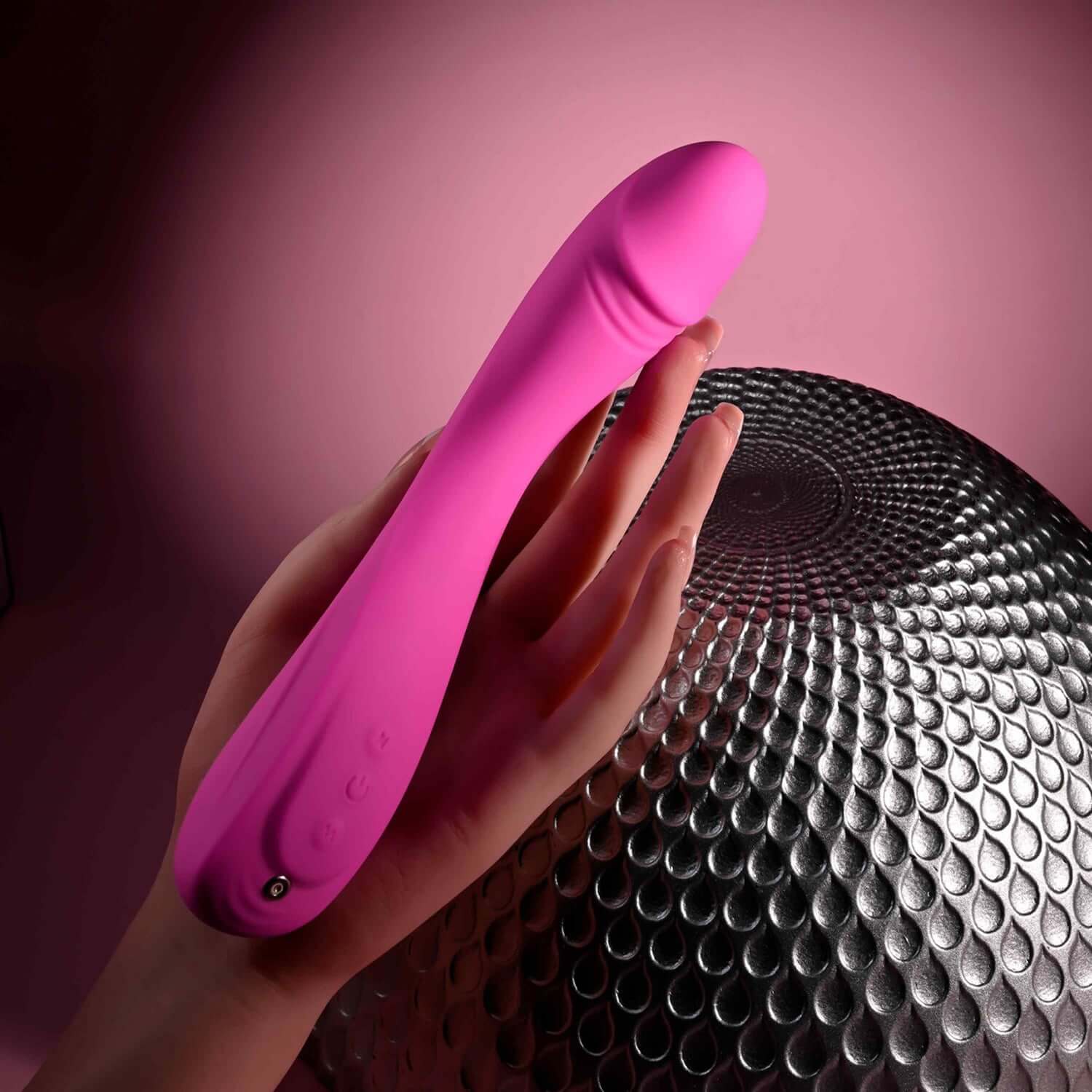 Elegant pink Sugar Rush vibrator held by a hand, showcasing its rounded head and flexible design over a textured background.