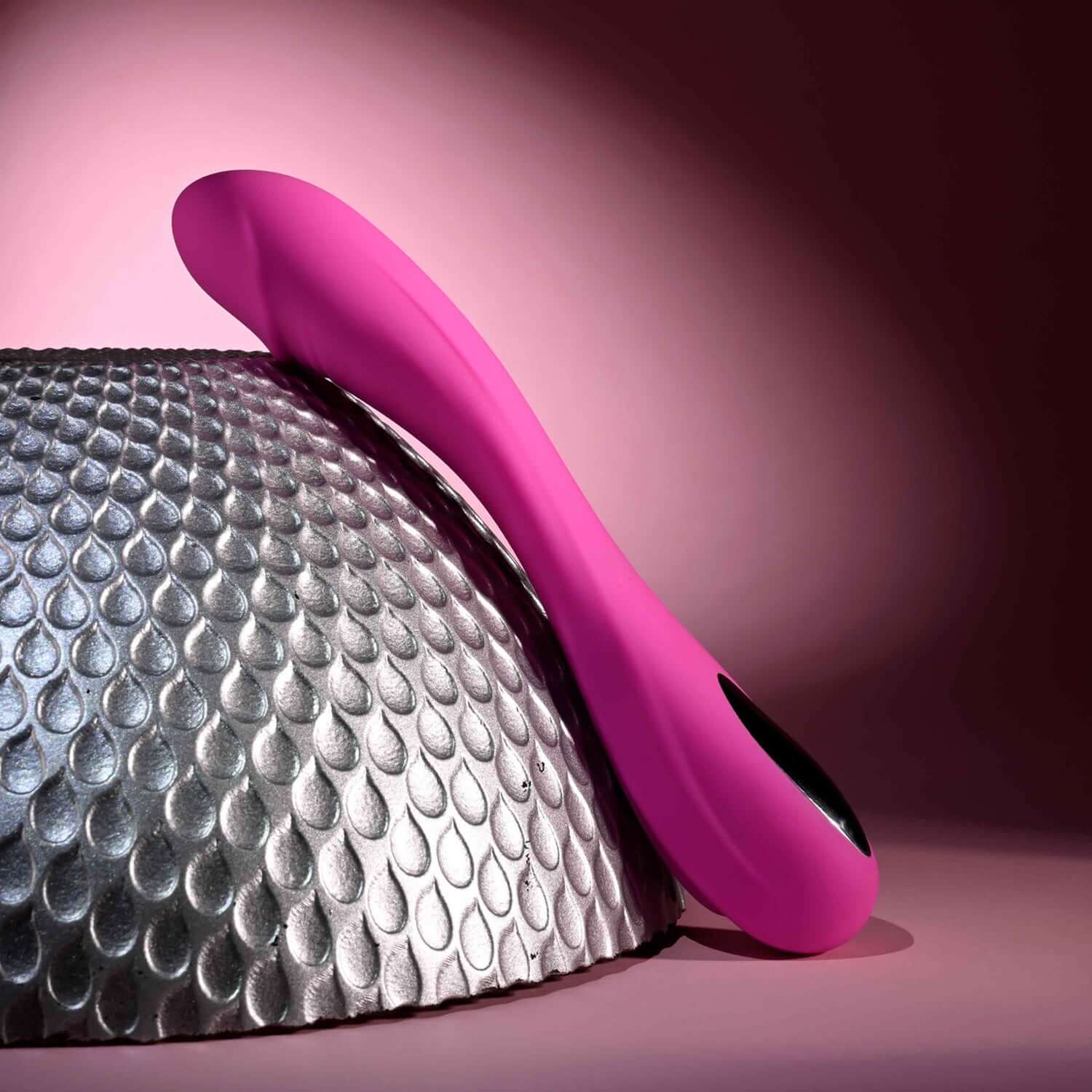 Elegant pink Sugar Rush vibrator resting on a textured surface, showcasing its flexible shape and ergonomic design.