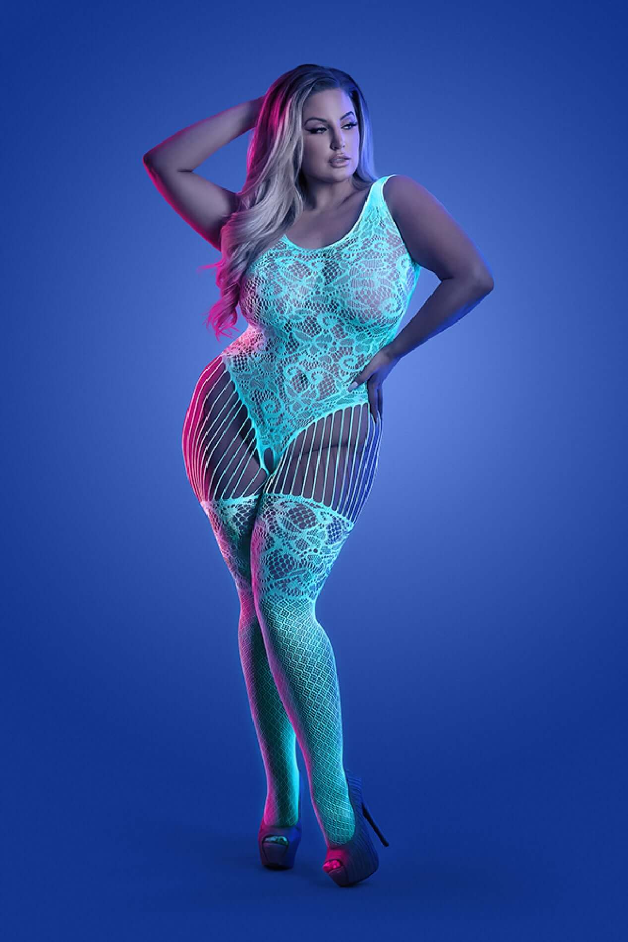 Glow-in-the-dark white and blue crotchless teddy bodystocking worn by a model in a blue background studio.