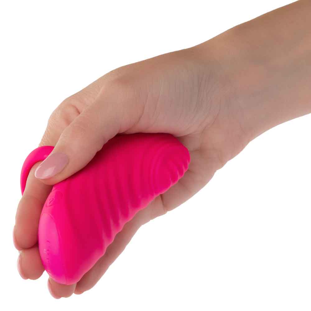 Hand holding Envy Handheld Thumping Massager in pink, showcasing its rippled texture and ergonomic design.