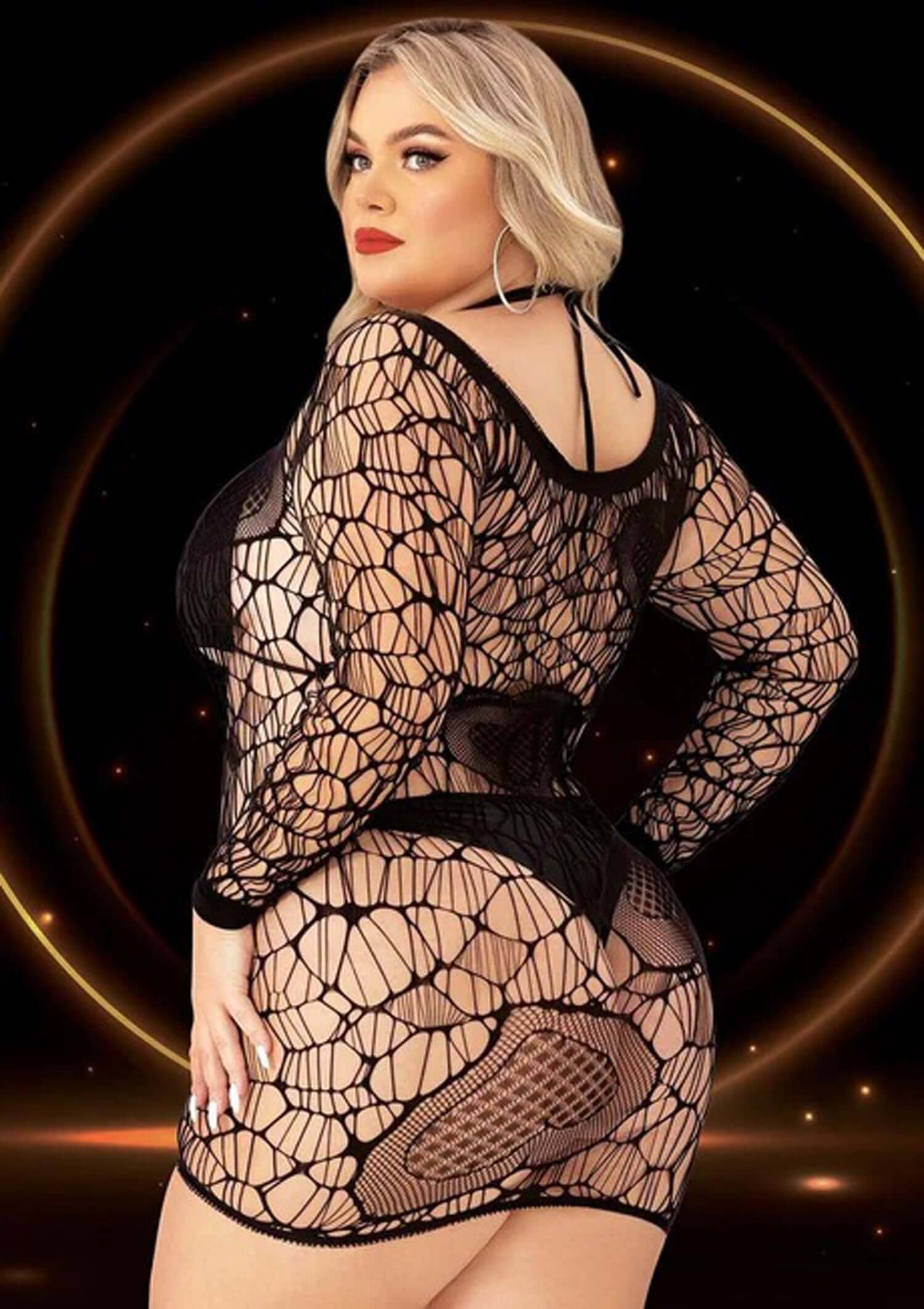 Plus size model showcasing a black long sleeve mini dress with daring cutouts, highlighting bold and sultry fashion.