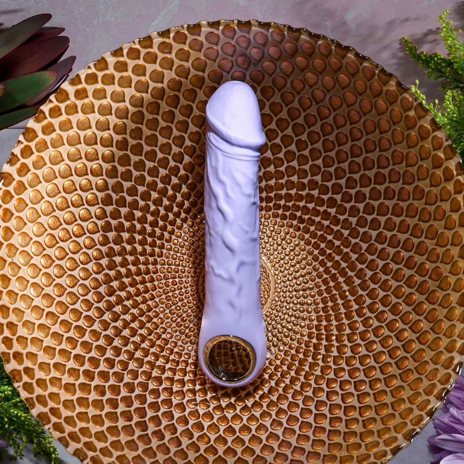 Purple Fantasy Vibrator on a decorative bowl, showcasing its lifelike design and chrome-finished handle for comfort.